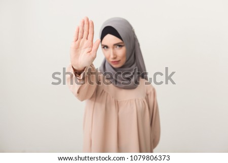 Young muslim woman in hijab doing stop gesture at studio background. Stop abuse and denial concept, copy space