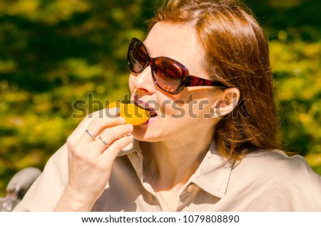 Pretty woman bite wellness snack cookie on work break.Close up girl face eating rounded biscuit outdoor on summer day.
