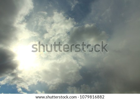 Blue sky and gray clouds. The sun shines through thunderclouds. Background. Landscape.