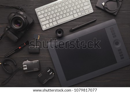 Top view on workplace of photographer or creative designer. Desk with graphic tablet, laptop, camera, lens and other photographic equipment