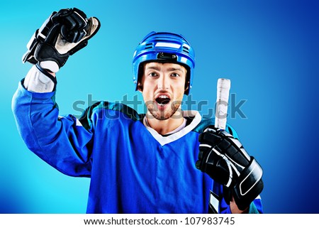 Portrait of a handsome ice-hockey player with hockey stick. Studio shot.