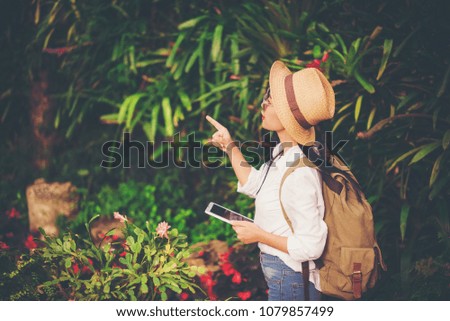 girl play the tablet  tourist travel in flower garden, Travel concept.