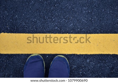 Standing on asphalt ground with yellow line on the road.