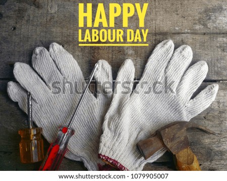 Concept of gloves, hammer, screwdriver on wooden background with word HAPPY LABOUR DAY.