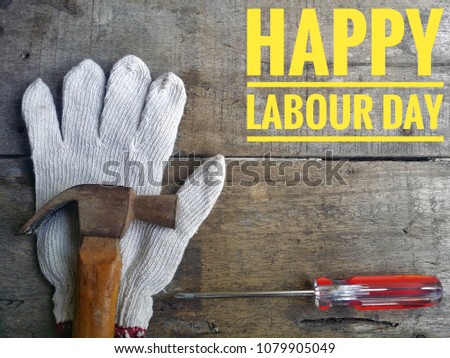 Concept of gloves, hammer, screwdriver on wooden background with word HAPPY LABOUR DAY.