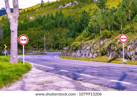 An empty curved road against the backdrop of the wooded slopes of the mountains. Road signs on the roadside. A tourist route for travel by Europe. Region of Batalha, Portugal.