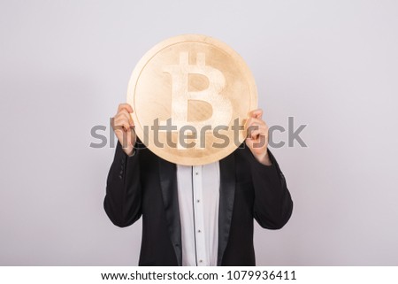 Businessnan holding big golden bitcoin on pink background. Crypto currency, virtual money, internet and economics concept