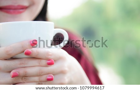 Closeup image of Asian woman smelling and drinking hot coffee with feeling good by natural,Top view image of Asian woman holding and smelling with hot milk and coffee feeling good outdoors,
