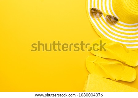 beach accessories on the yellow background - sunglasses, towel. flip-flops and striped hat. summer is coming concept Royalty-Free Stock Photo #1080004076