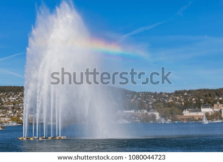 A fountain and boats on Lake Zurich in Switzerland, buildings of the city of Zurich in the background. The picture was taken at the beginning of October.