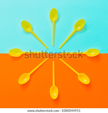 yellow plastic spoons on turquoise background. food time concept