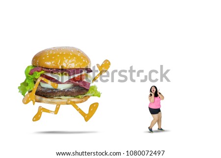 Picture of big hamburger chasing fat woman while running in the studio, isolated on white background