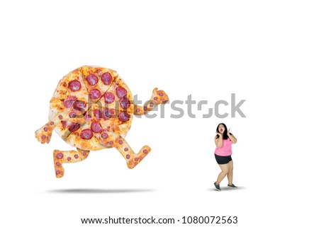 Picture of young overweight woman chased by a big pizza with scared expression, isolated on white background