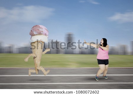 Picture of obese woman escaping from an ice cream while running on the track 