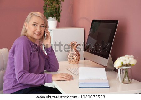 Mature woman talking on mobile phone at workplace