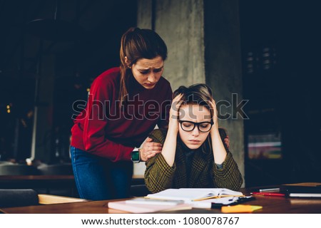 Sympathetic young woman supporting despaired student wich don't understand confused studying information during exam preparation in coworking.Exhausted hipster girl learning material from textbook Royalty-Free Stock Photo #1080078767