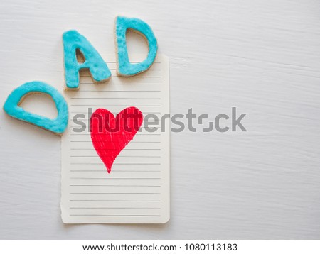Postcard with painted red heart and word DAD on white, isolated background. Top view. Congratulation to the father. Preparation for Father's Day