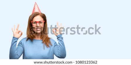 Middle age woman celebrates birthday doing ok sign gesture with both hands expressing meditation and relaxation isolated blue background