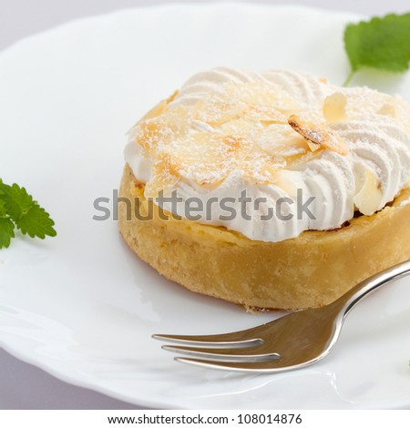 Close up of fresh lemon tart on white plate with a fork