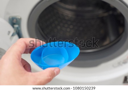 washerman putting the washing machine with the blue plastic detergent dispenser to save and make a more effective washing in savings and respect for the environment