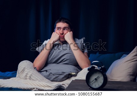 Picture of brunet with insomnia with pillow sitting next to alarm