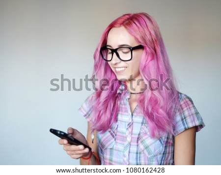 Portrait of a young girl with pink hair, with a mobile phone
