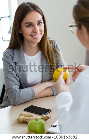 Shot of beautiful young dietician explaining to her patient the properties of the lemon in the consultation.