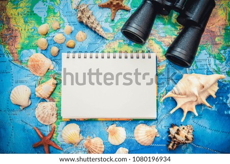 The picture on the subject of vacation and travel at sea: binoculars, shells, starfish, notebook with copy space
