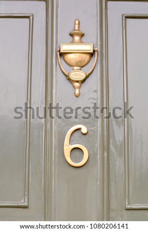 House number 6 sign on green door with brass door knocker