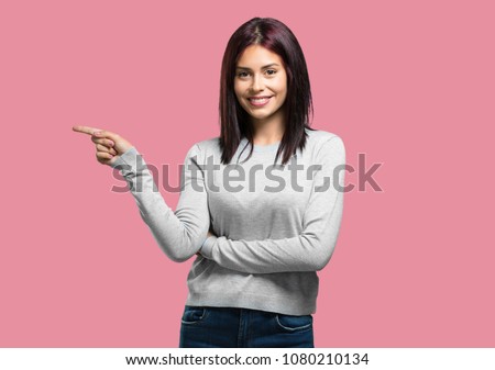 Young pretty woman pointing to the side, smiling surprised presenting something, natural and casual