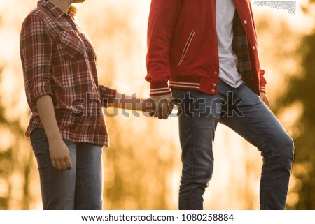 I love you!Girl and boy holding hands because they are in love. Boy is leading girl on hill. They are in beautiful warm summer light background during sunset, love is in the air, relationship,trust