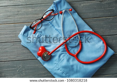 Stethoscope with doctor's uniform on wooden background. Health care concept