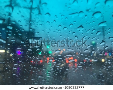 Water Drops on the windshield, traffic in the city on a rainy day at evening, car windshield view, colorful bokeh, dark and blurred background.