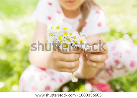 Happy little girl in nature with daisy bouquet at flower meadow, beautiful spring day 