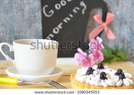 Cup of coffee with three cakes on a black background and a "good morning" text