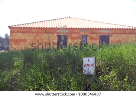 sign indicating that land and house under construction are for sale in a rural area