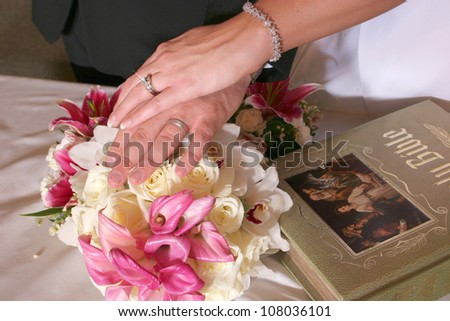 Bride and Groom hands on bible with flowers