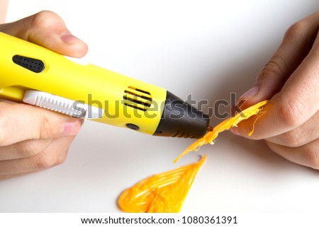 Kids hand holding yellow 3d printing pen with filaments and makes heart..