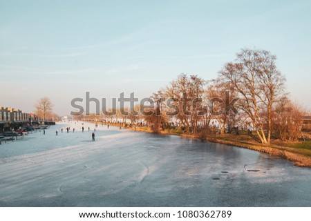 Scene of skating people on a canal and a lake. Gouda, the Netherlands.