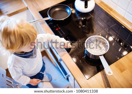 Toddler boy in dangerous situation at home. Child safety concept. Royalty-Free Stock Photo #1080411338