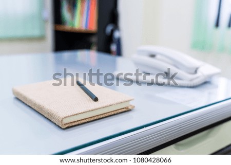 Book with pencil placed on a desk at the office.
