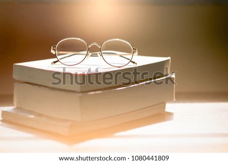 desk workplace.Close up eyes glasses on books in the morning blurred background.