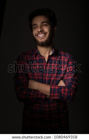 Portrait of a handsome young man wearing a casual outfit, stand crossed hands and smiling.