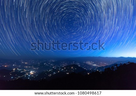 Night sky star trails around the North star with city lights in the background taken from the top of a hill in himalayas Royalty-Free Stock Photo #1080498617