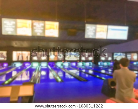 Blurred bowling alley and lounge area at entertainment complex in America, big TV screen display scores