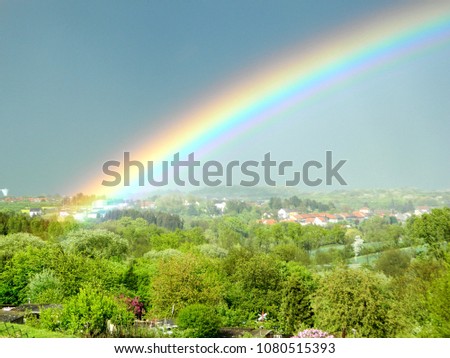 Rainbow in the background of a rural landscape. The French village.