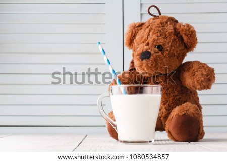 Teddy bear with milk drain on a wooden background