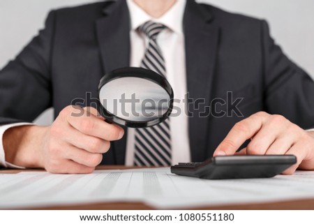 Businessman holding magnifying glass zoom and looking to documents