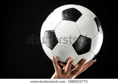 Classic soccer ball on female hand. Isolated over black background