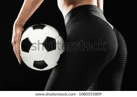 Beautiful woman holding a soccer ball on black background